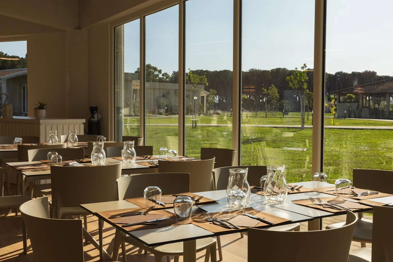 Sala ristorante con tavoli apparecchiati e grandi vetrate sul giardino