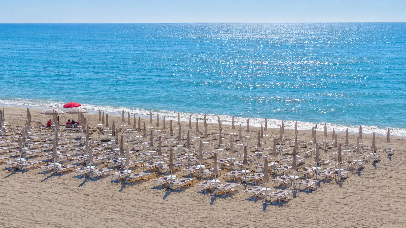 Veduta della spiaggia con lettini, ombrelloni e mare azzurro scintillante