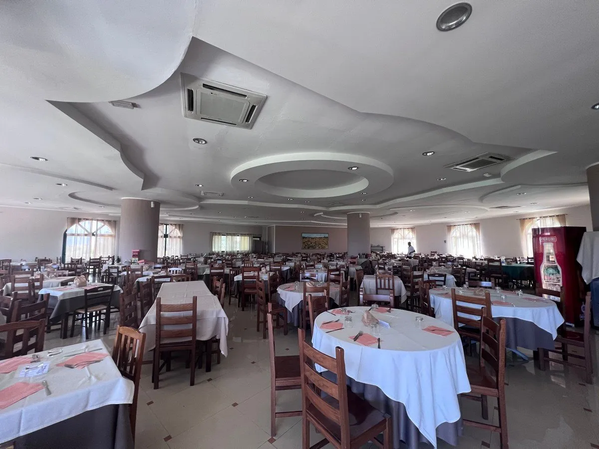 Ampia sala ristorante con tavoli rotondi e quadrati apparecchiati