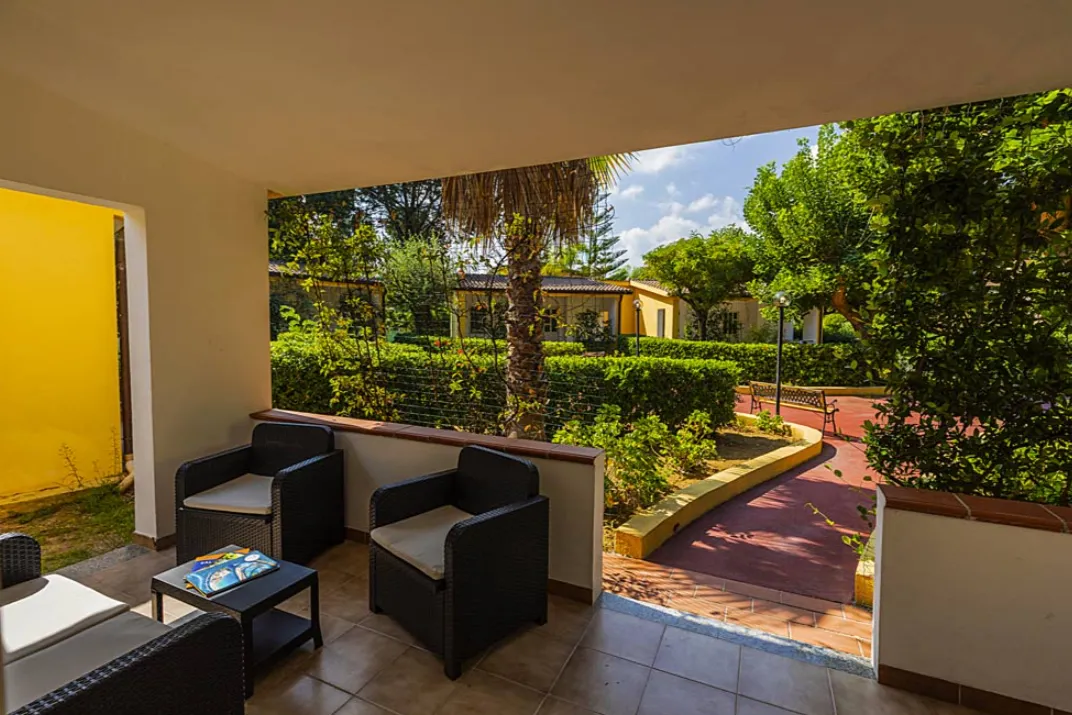 Veranda con poltrone in rattan affacciata sul vialetto del giardino