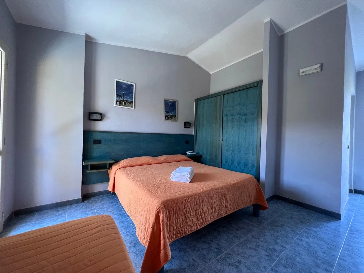 Camera con letto matrimoniale e singolo, copriletto arancione e armadio