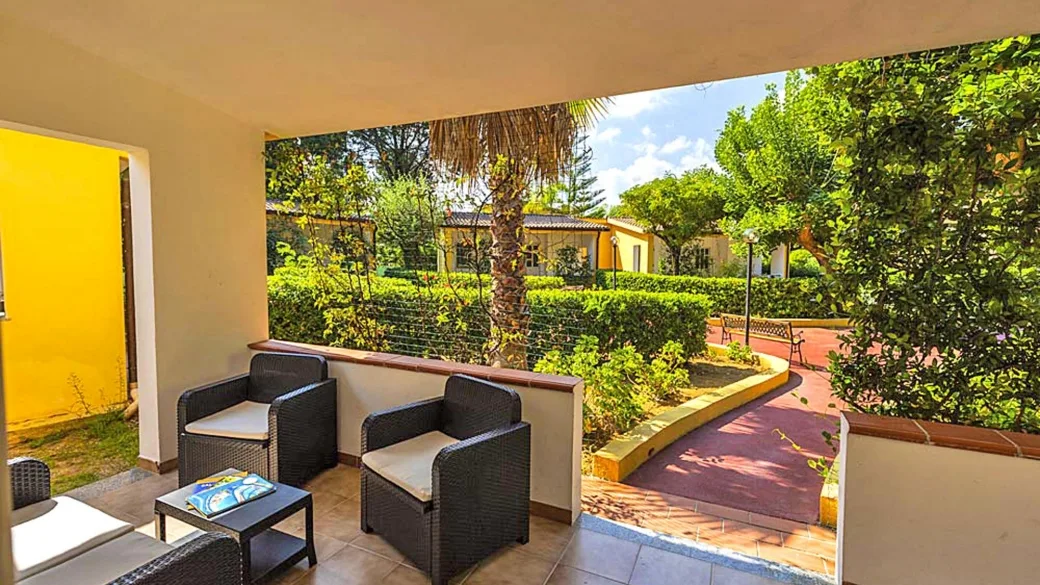 Veranda con poltrone in rattan vista giardino e vegetazione del resort