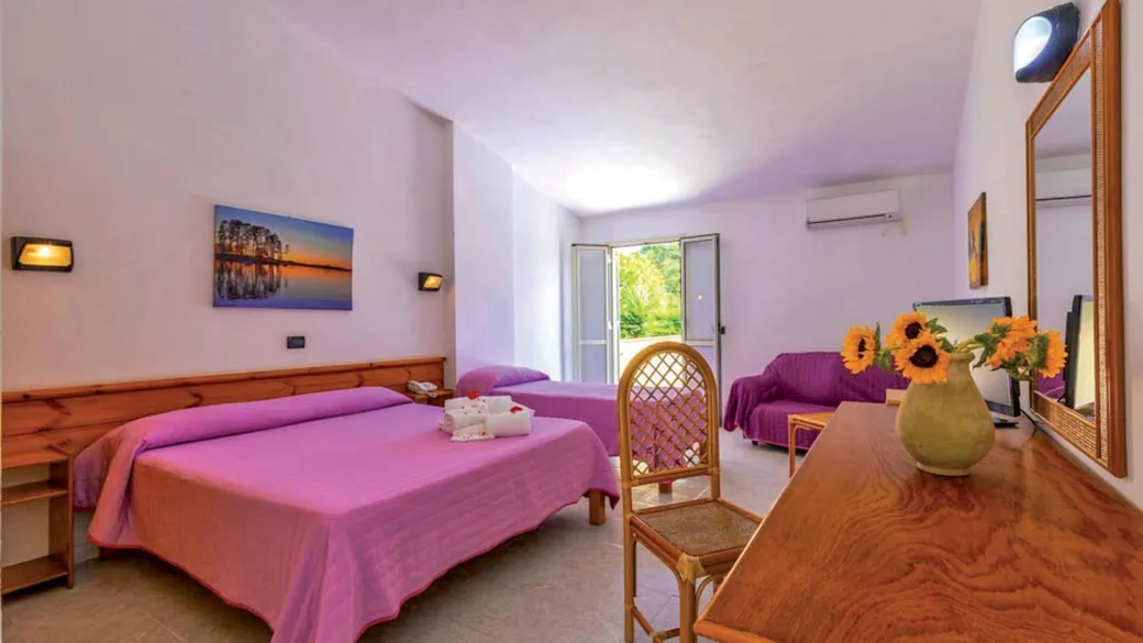 Camera con letto matrimoniale, divano viola e affaccio sul giardino