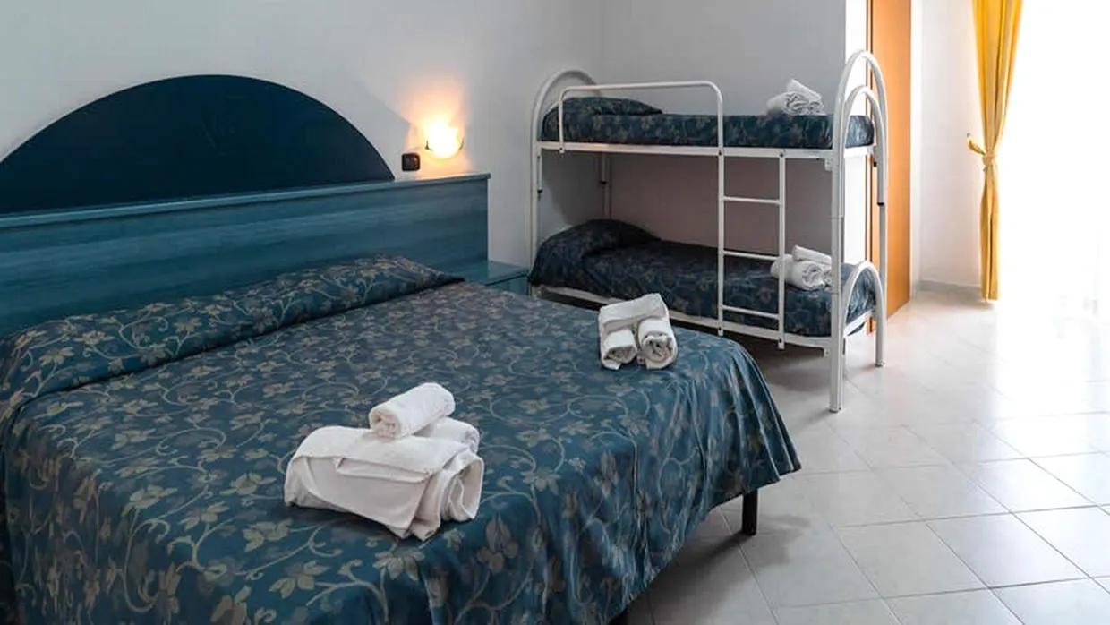 Camera con letto matrimoniale e letto a castello, arredi blu e pavimento chiaro