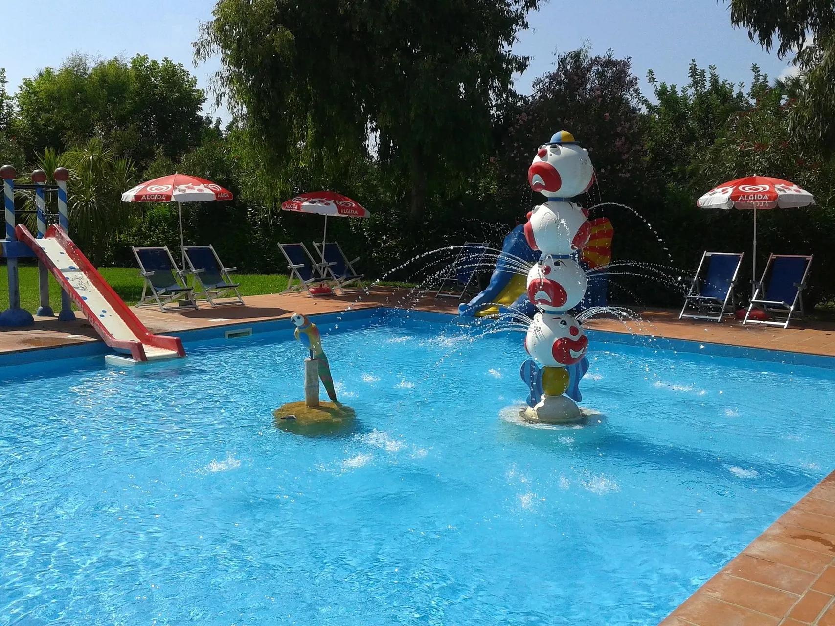 Piscina per bambini con giochi d'acqua, scivolo e ombrelloni