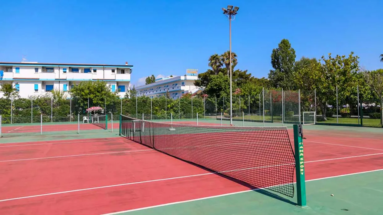 Campo da tennis in terra rossa con edifici dell'hotel sullo sfondo
