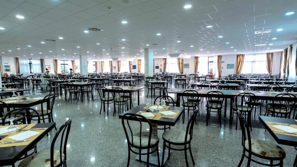 Ampia sala ristorante con tavoli apparecchiati e grandi finestre