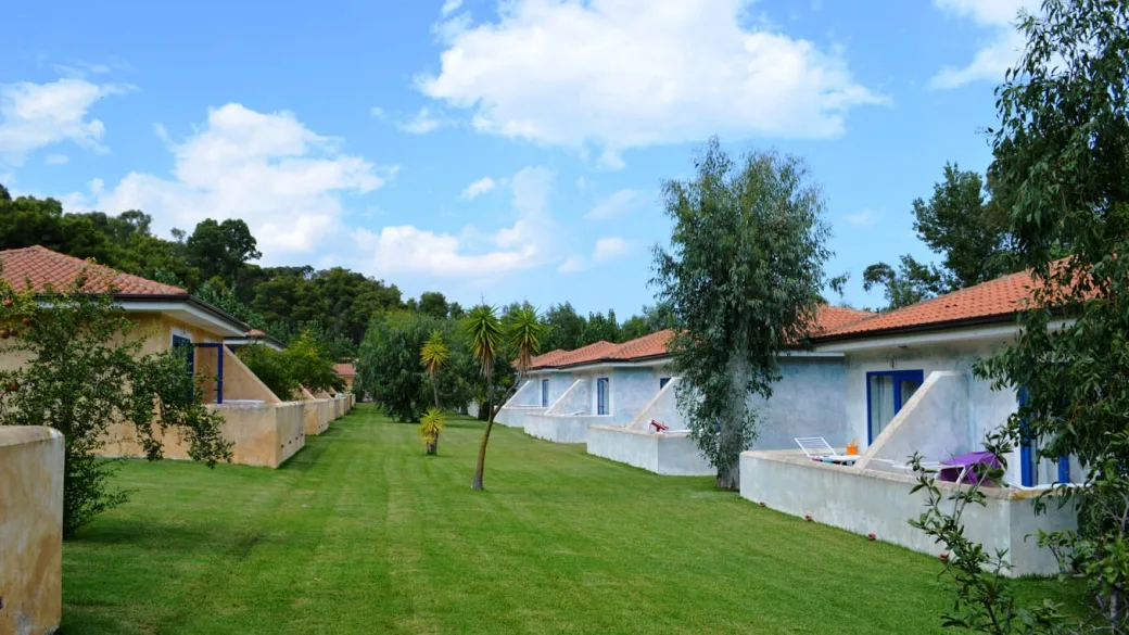 Casette del resort con tetti in tegole disposte su prato verde curato sotto cielo azzurro