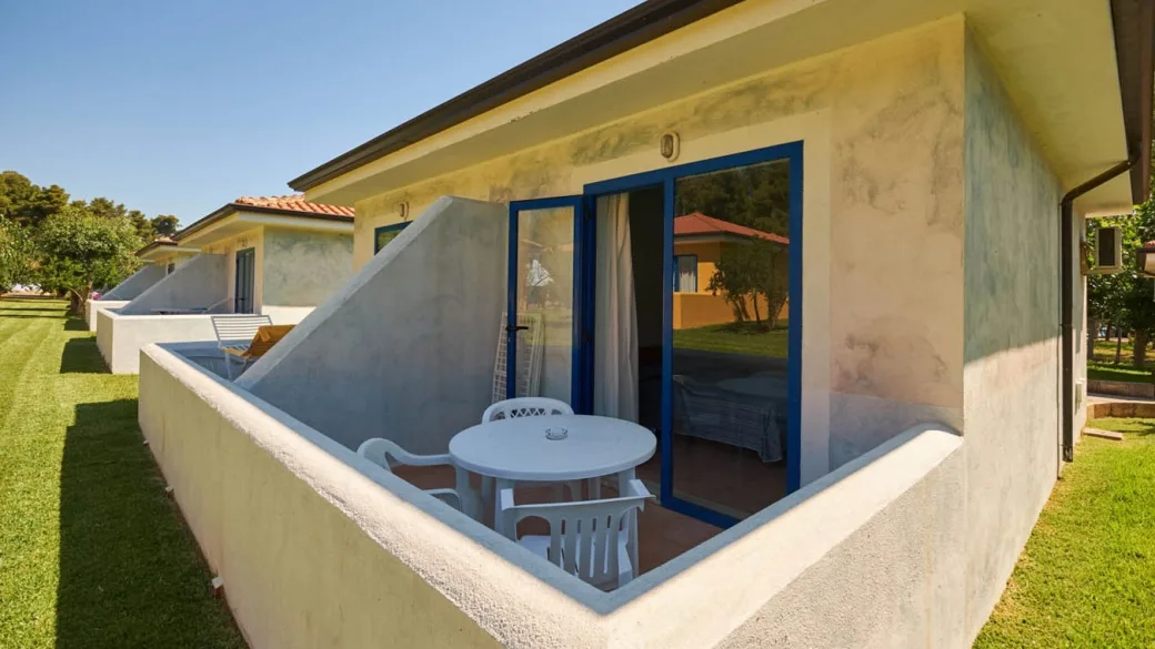 Veranda esterna di una casetta con tavolino, sedie e vista sul giardino