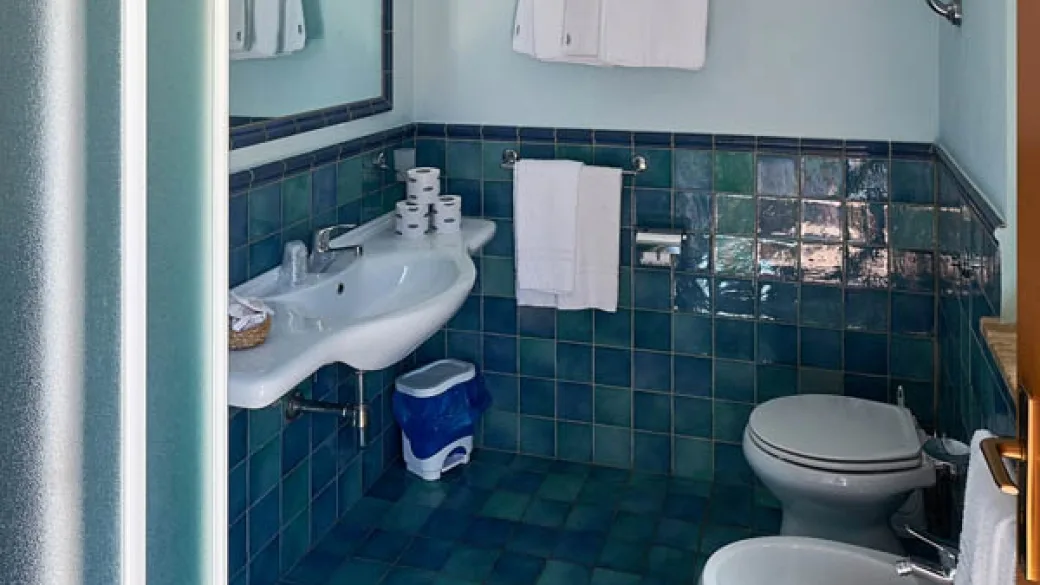 Bagno con piastrelle verdi e blu, lavabo, sanitari e doccia