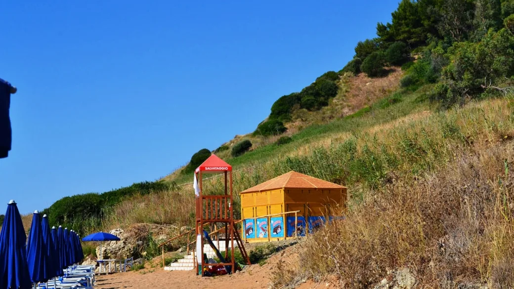 Torretta di salvataggio e capanno sulla spiaggia ai piedi di una collina verdeggiante