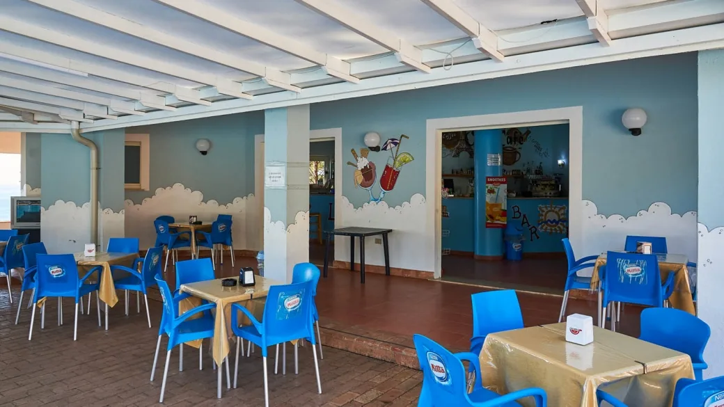 Bar del resort con tavoli e sedie blu, decorazioni a tema e ambiente colorato
