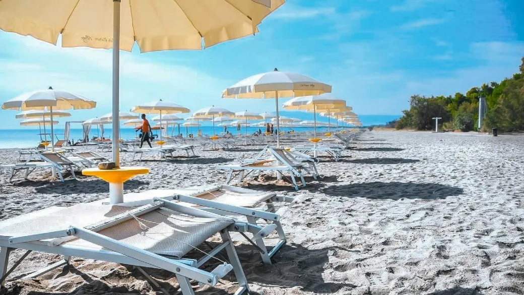 Spiaggia attrezzata con lettini e ombrelloni bianchi vicino al mare