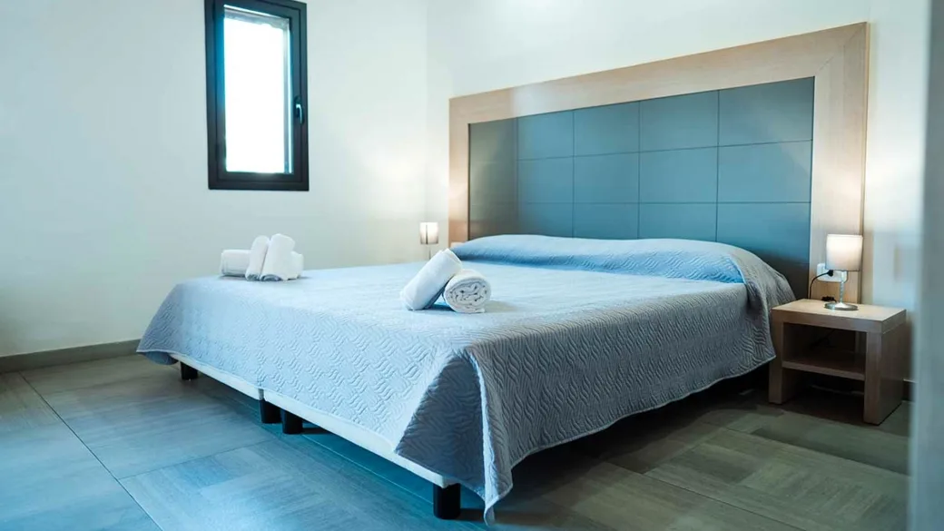 Camera da letto con letto matrimoniale e testiera blu, ambiente luminoso