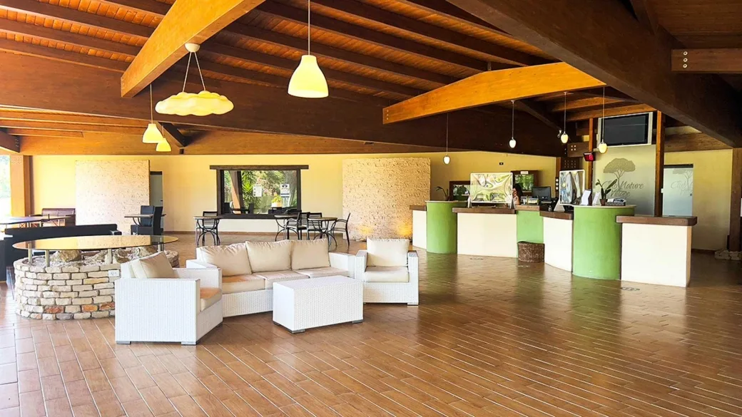 Reception con soffitto in legno, divani bianchi e banco accoglienza