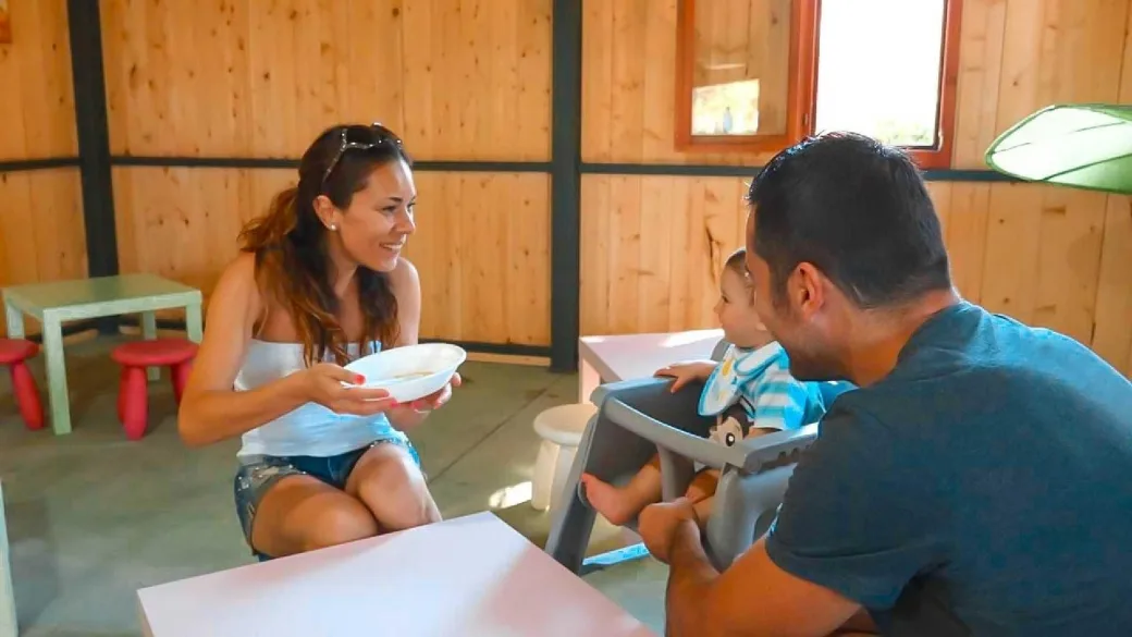 Genitori con bambino su seggiolone in ambiente in legno per famiglie