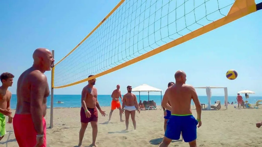 Gruppo di persone che gioca a beach volley in spiaggia vicino al mare
