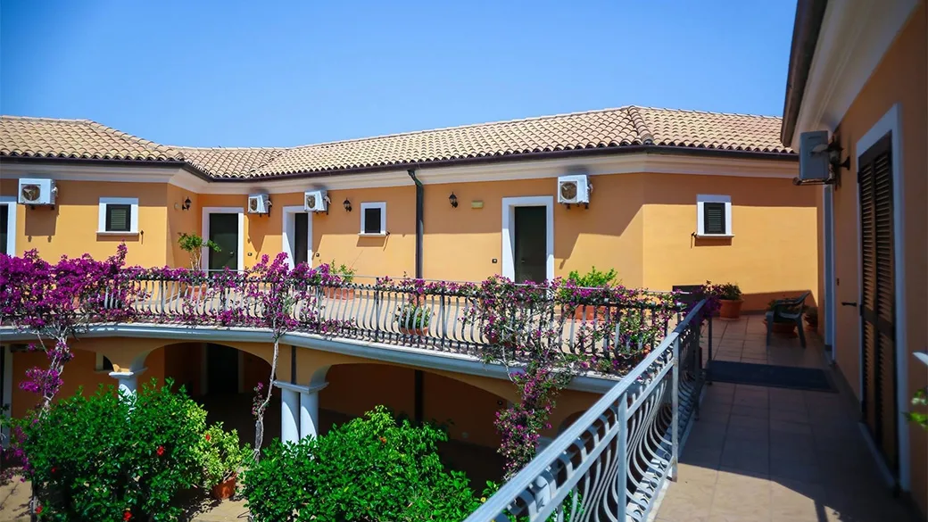 Cortile interno con balconi fioriti di bouganville e tetti in coppi