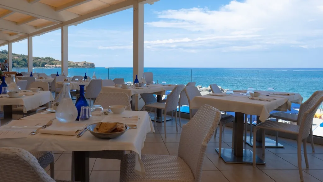 Terrazza ristorante con tavoli apparecchiati e vista panoramica sul mare
