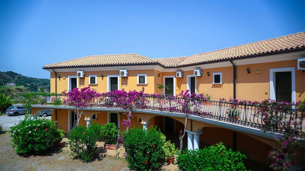 Edificio arancione con balconata fiorita di bouganville e cortile