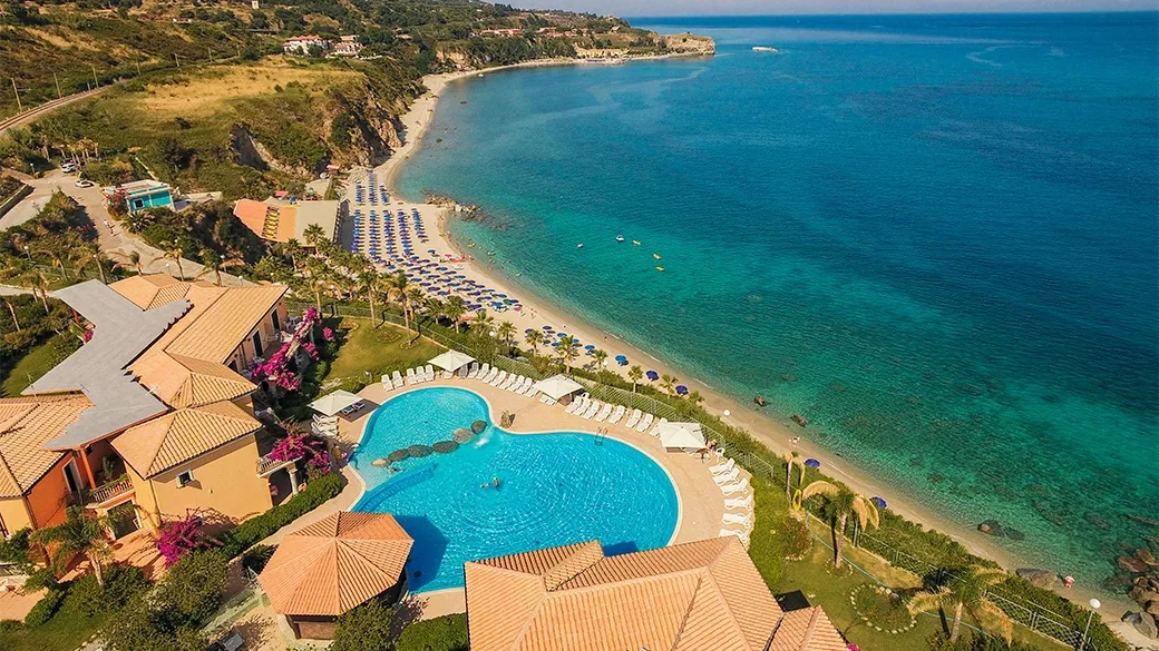 Panoramica del resort con grande piscina, spiaggia e baia sul mare blu