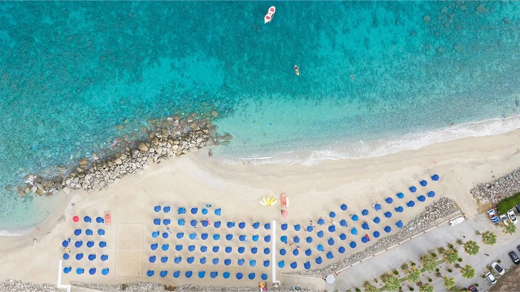 Veduta aerea della spiaggia con ombrelloni blu e mare turchese