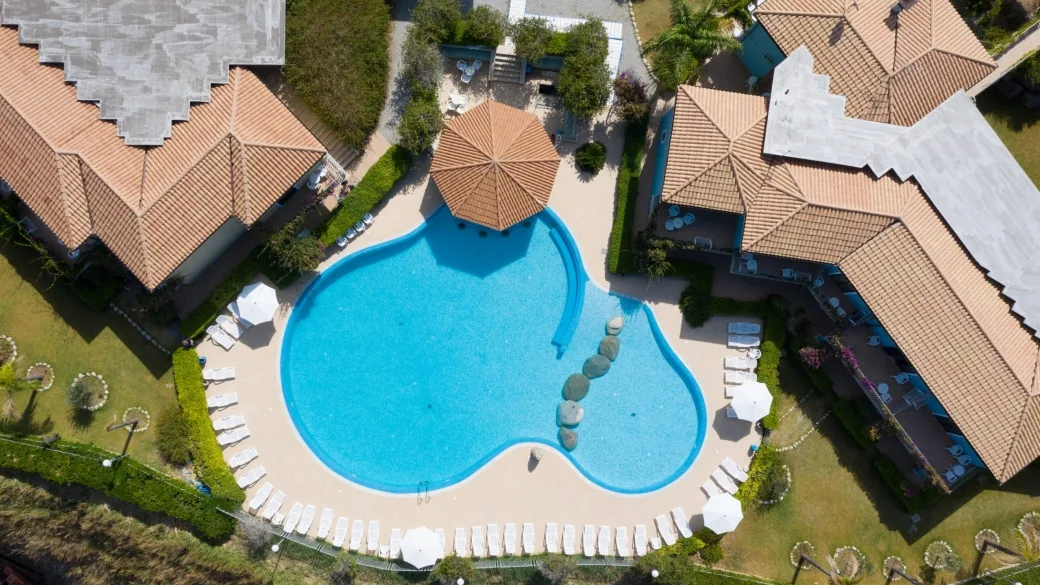 Piscina a forma di cuore vista dall'alto con lettini e tetti in coppi