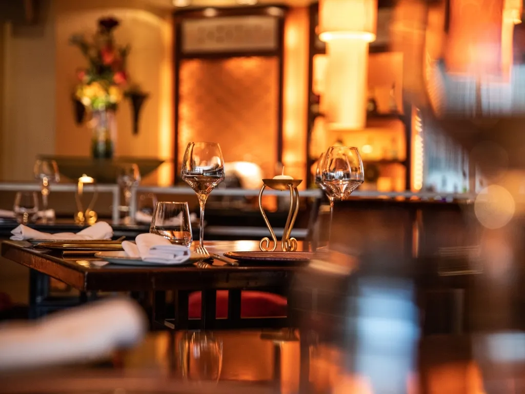Tavolo del ristorante elegantemente apparecchiato con calici e atmosfera calda