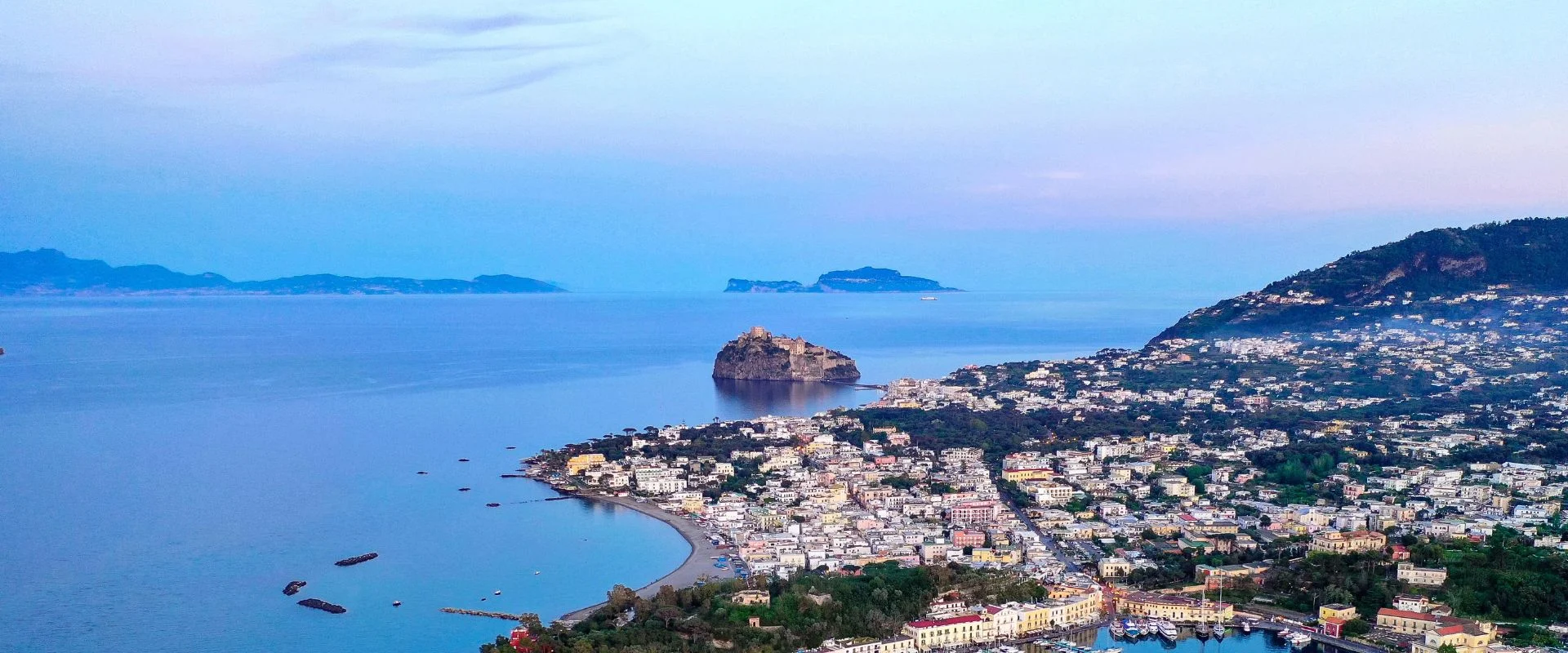 Panorama al tramonto di Ischia con il Castello Aragonese e la costa illuminata
