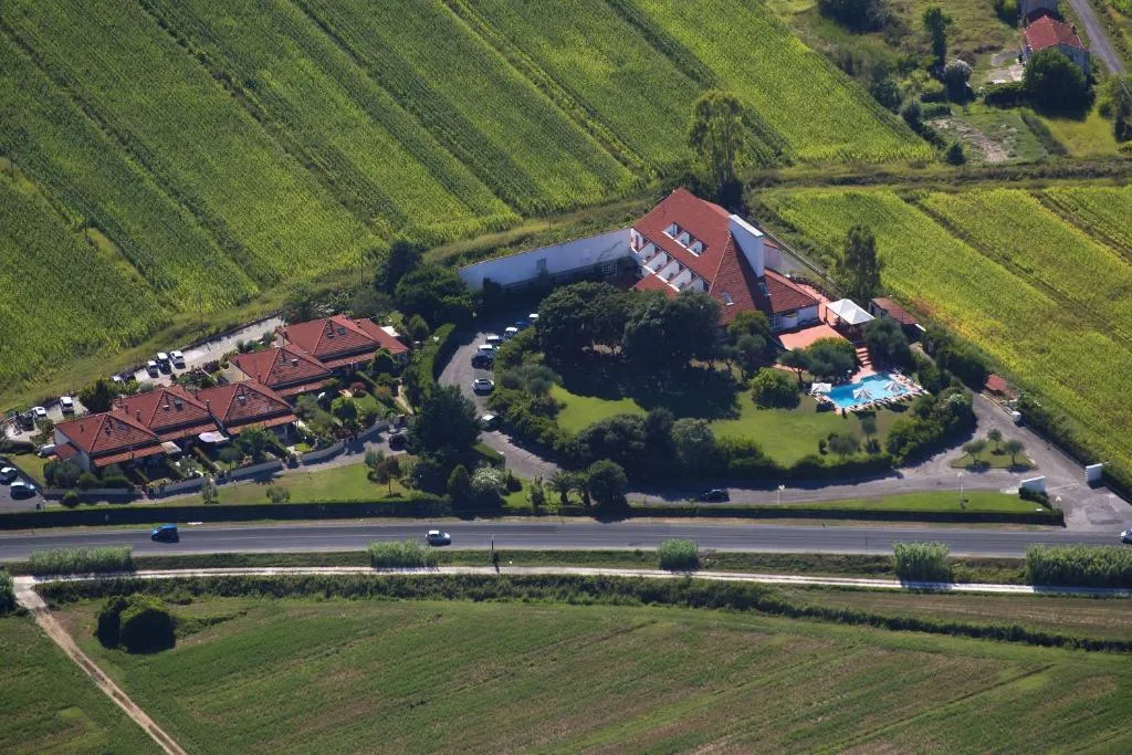 Veduta aerea dell'hotel con tetti rossi, piscina, giardino e campi coltivati circostanti