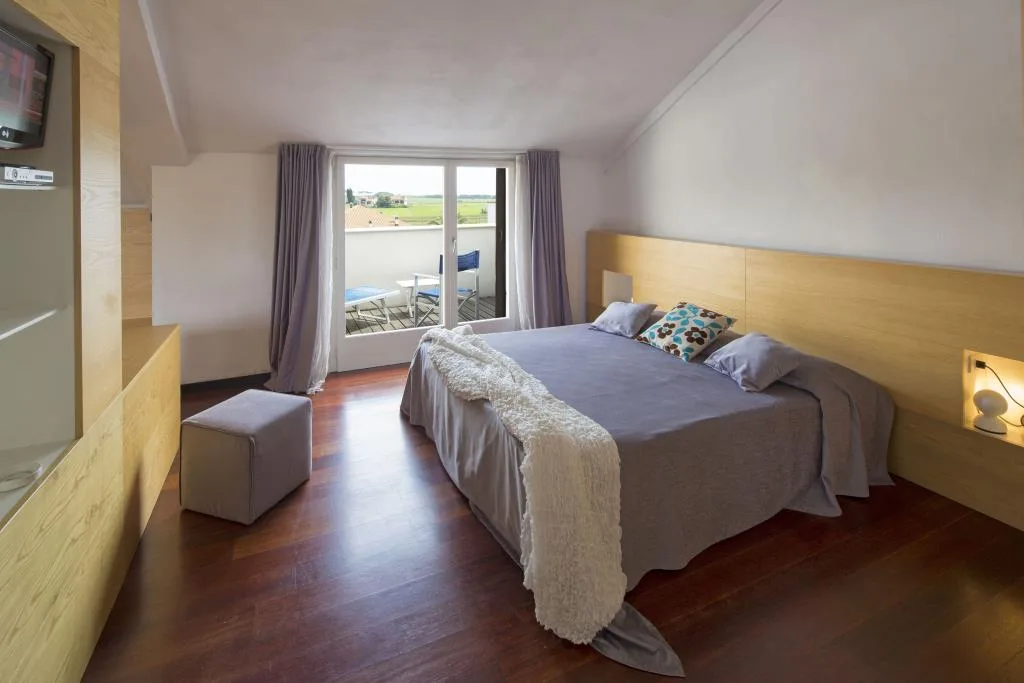 Camera mansardata con letto matrimoniale, arredi in legno e ampia terrazza panoramica