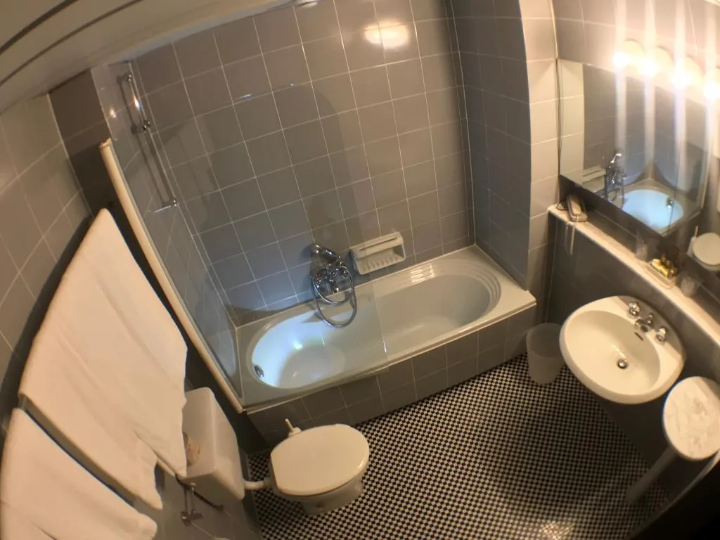 Bagno con vasca, sanitari bianchi e pavimento a mosaico bianco e nero