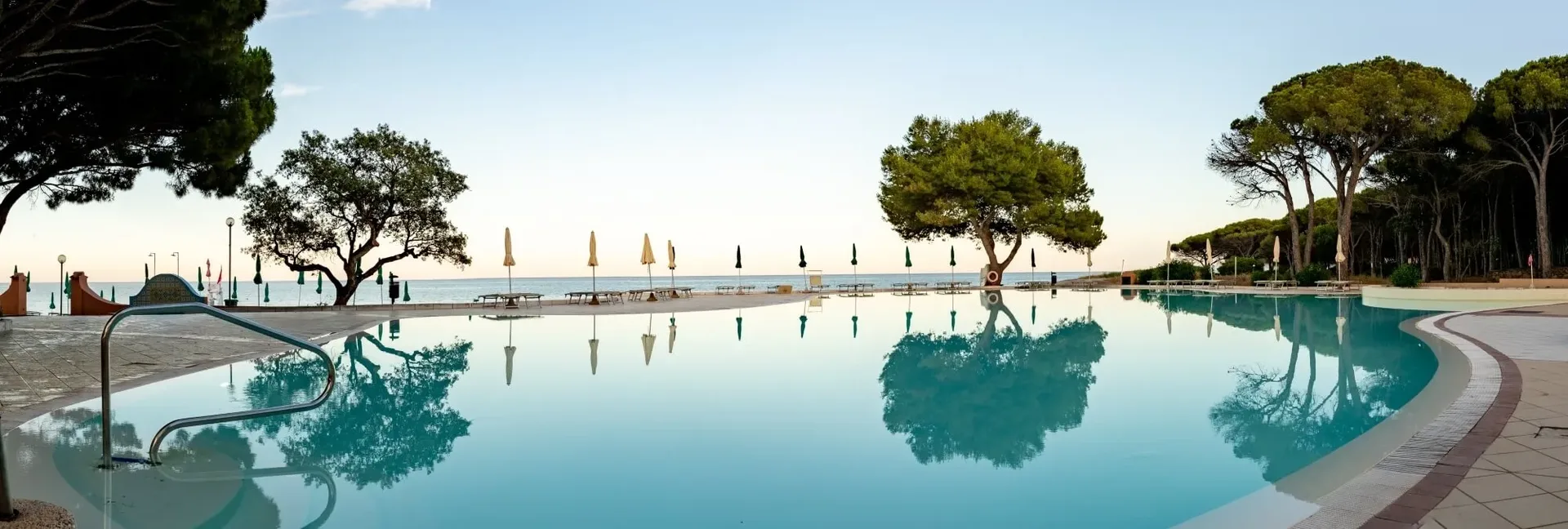 Vista panoramica della grande piscina con riflessi degli alberi sul mare