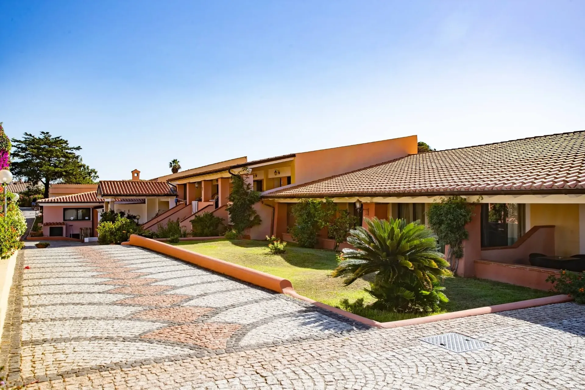 Edifici in stile mediterraneo color terracotta con giardini e palme