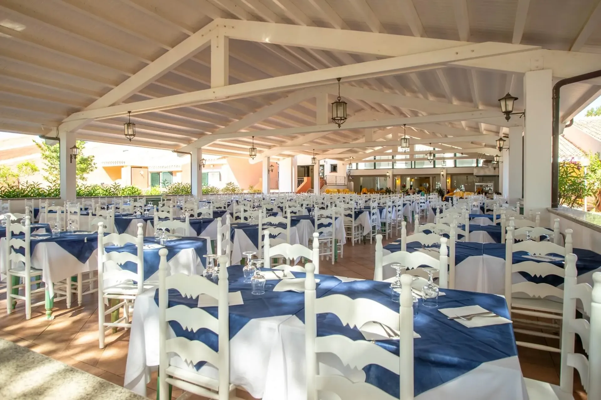 Sala ristorante coperta con tavoli blu e bianchi e sedie bianche