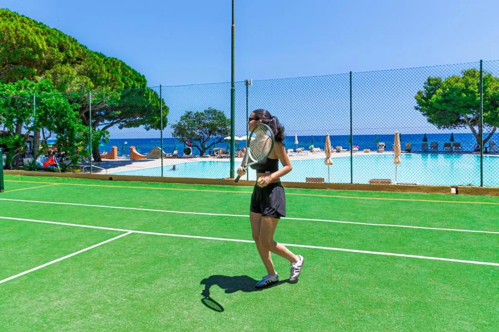 Donna gioca a tennis sul campo con piscina e mare sullo sfondo