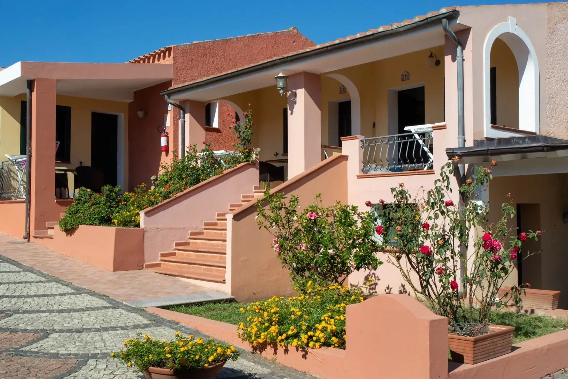 Bungalow color terracotta con scalinate, balconi e giardini fioriti