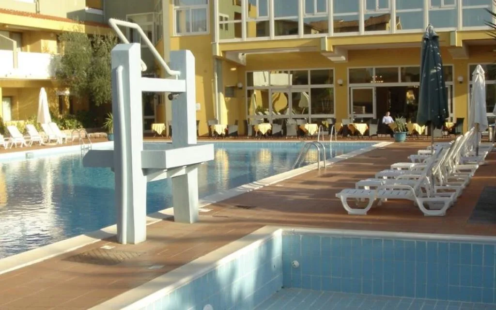 Bordo piscina con lettini e tavoli del ristorante sullo sfondo
