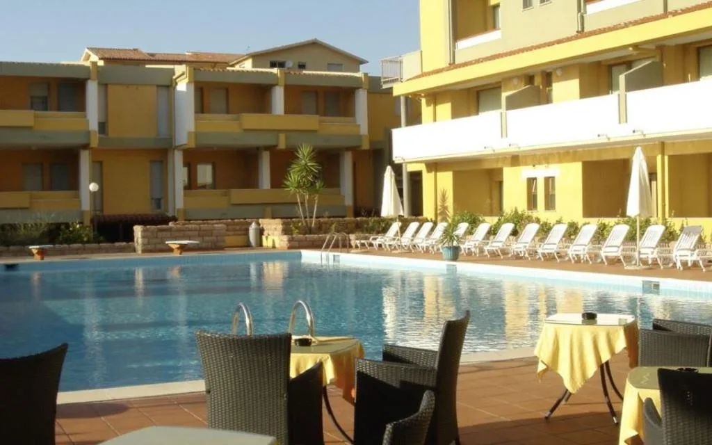 Piscina con lettini bianchi e tavoli del bar nel cortile dell'hotel