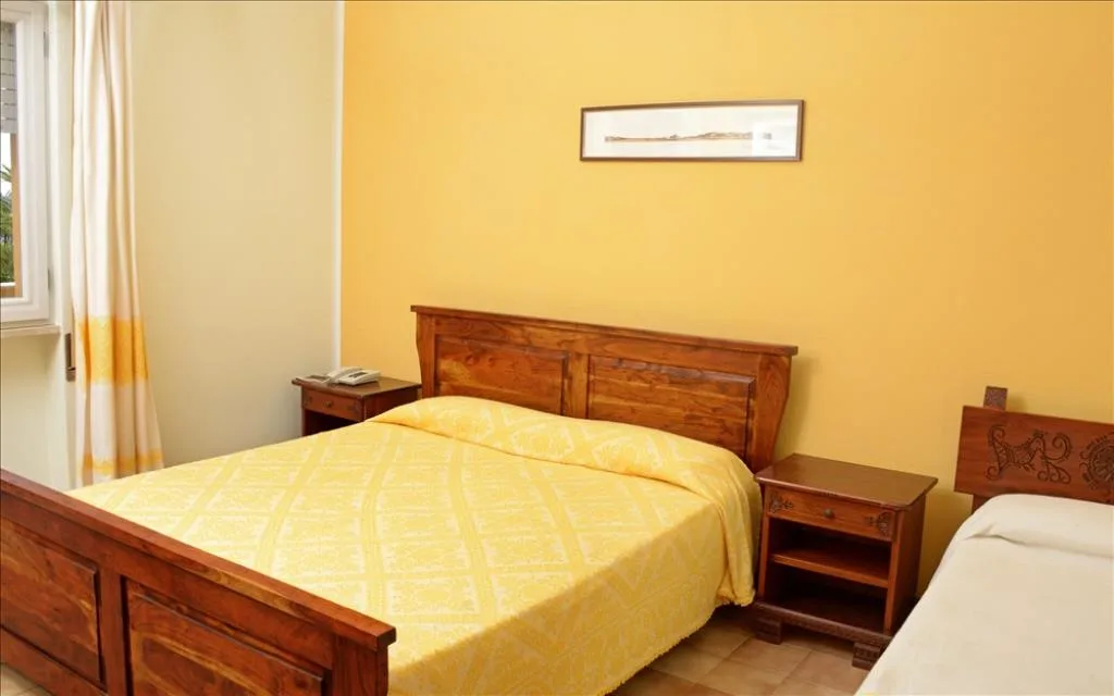 Camera con letto matrimoniale e copriletto giallo, mobili in legno