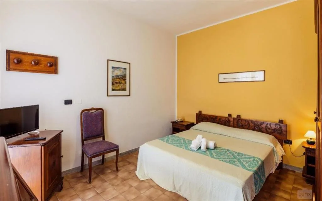 Camera con letto matrimoniale, parete gialla e mobili in legno