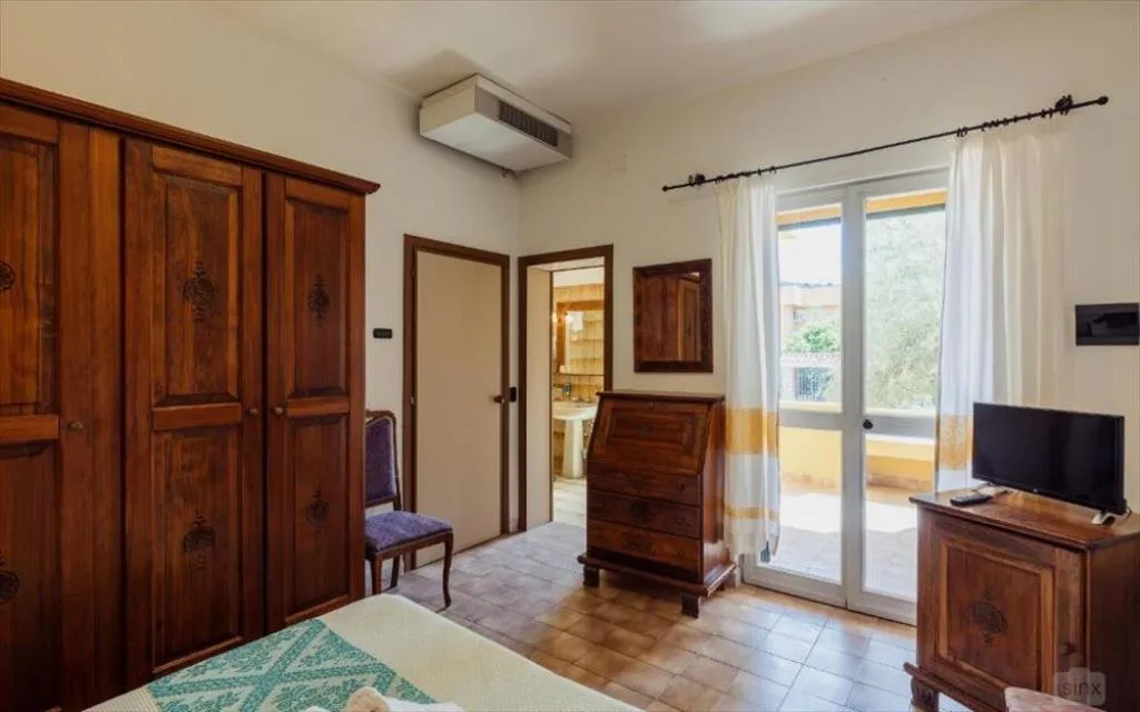 Camera con armadio in legno e porta finestra sul balcone
