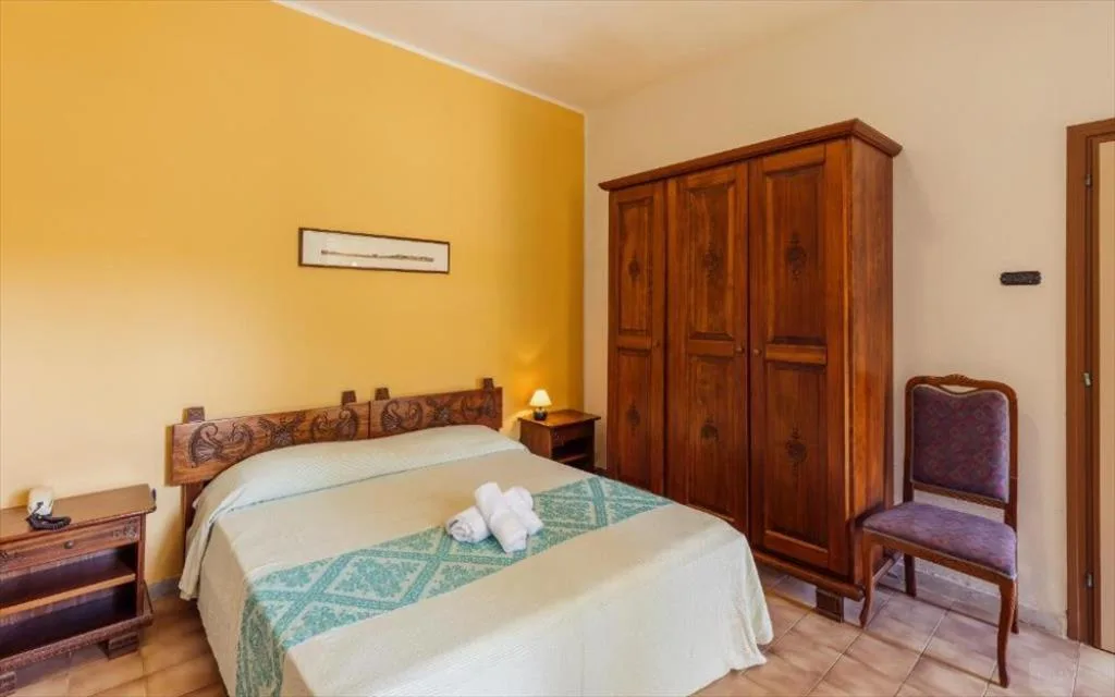 Camera con parete gialla, armadio in legno e copriletto bianco