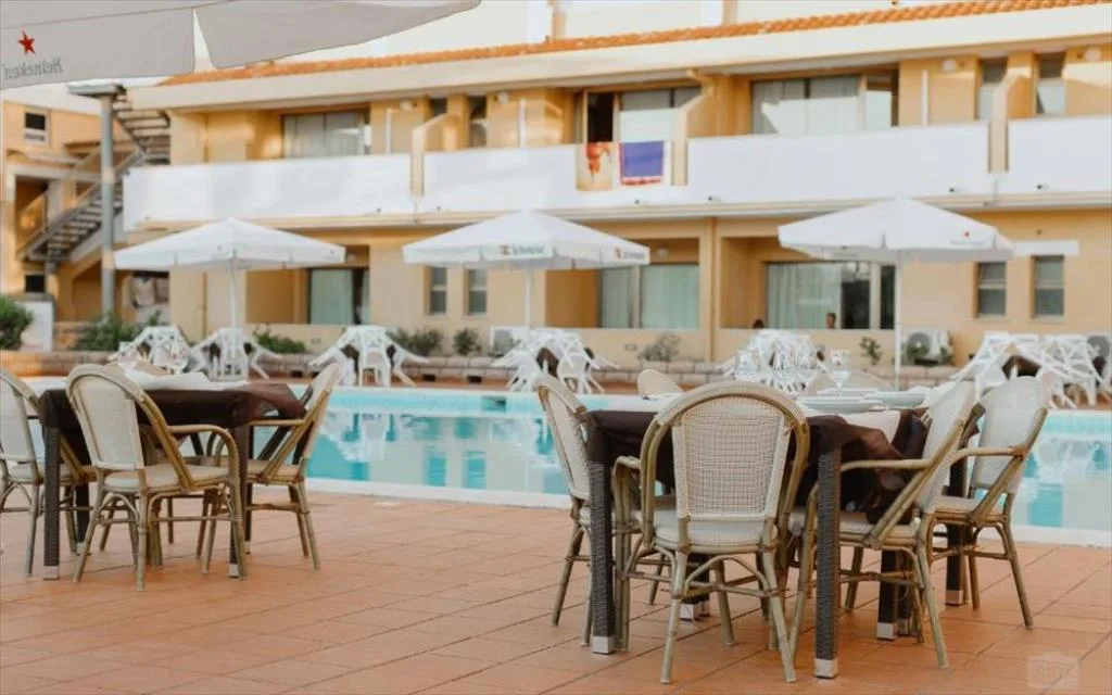 Tavoli del ristorante all'aperto a bordo piscina con ombrelloni
