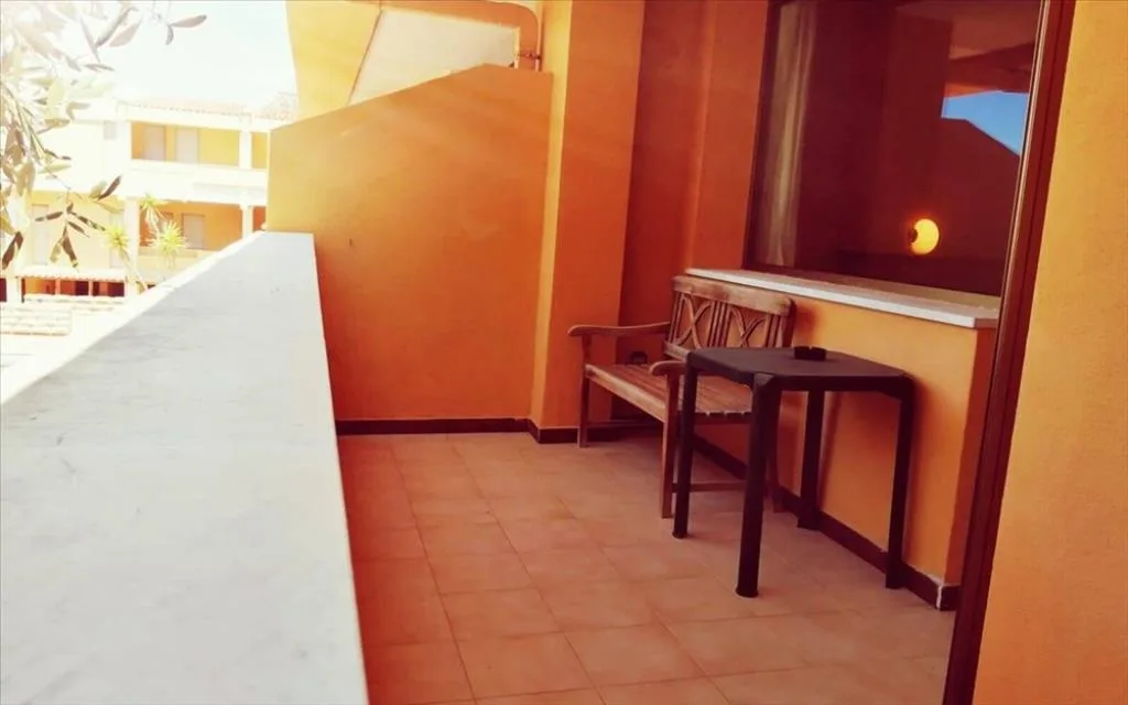 Balcone con panchina in legno e tavolino, pareti arancioni