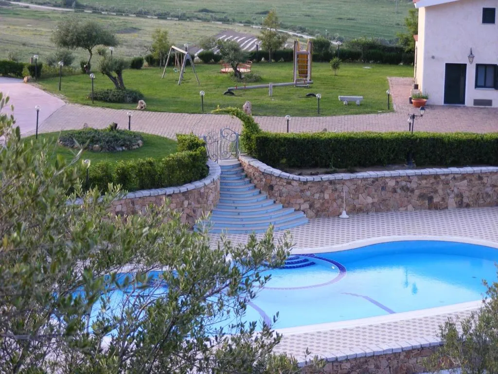 Area piscina con scalinata azzurra, giardino verde e parco giochi sullo sfondo