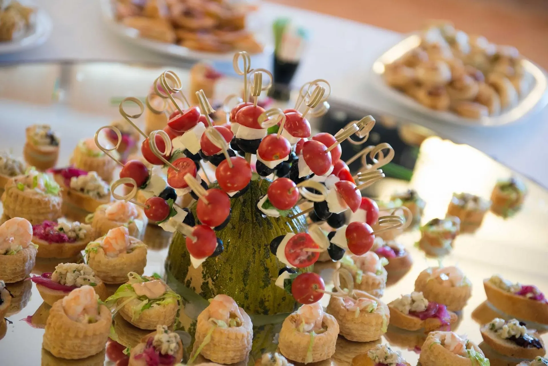 Buffet con tartine, spiedini di pomodorini e mozzarella su zucca decorativa