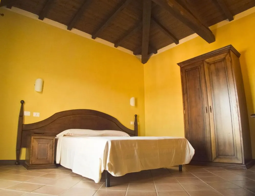 Camera da letto con pareti gialle, soffitto in travi di legno e armadio in legno