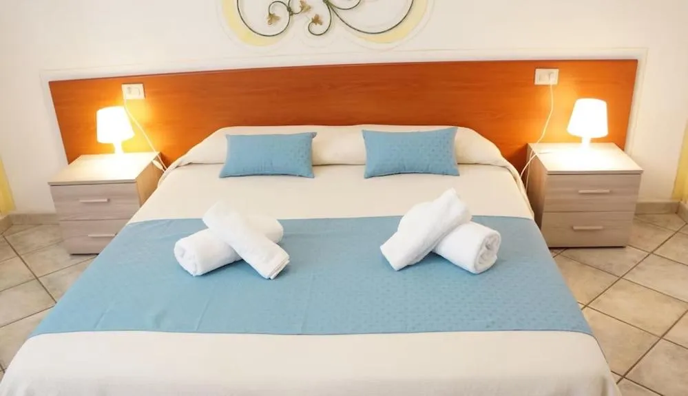 Camera da letto con letto matrimoniale, testiera in legno, asciugamani arrotolati e comodini con lampade