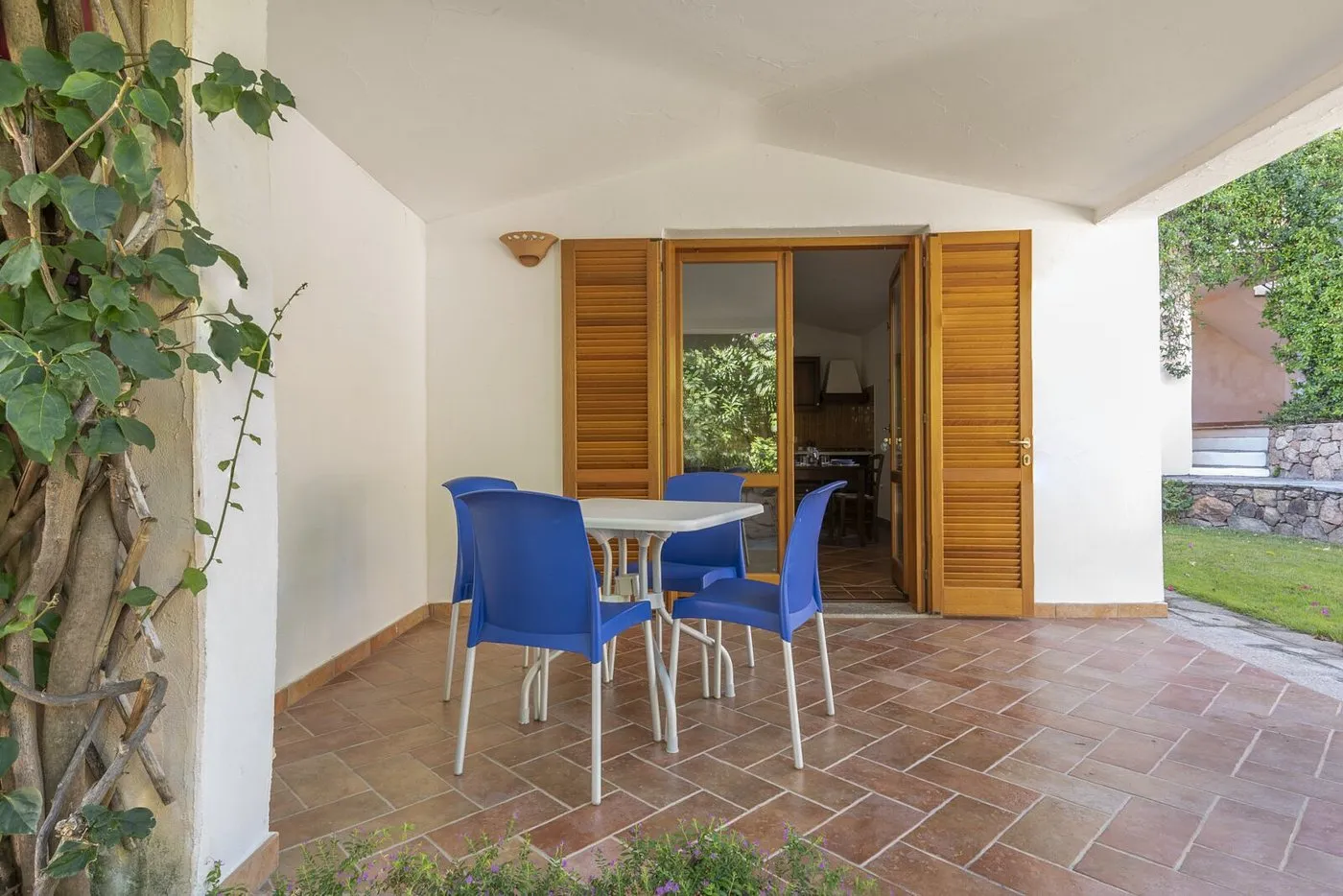 Veranda coperta con tavolo e sedie blu affacciata sul giardino